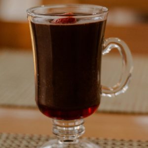 A close-up of mulled wine in a clear glass cup, perfect for cozy winter evenings.
